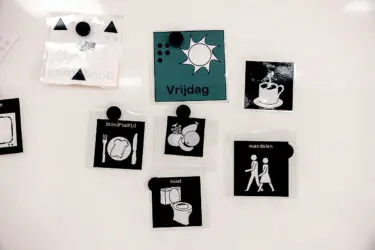 Plaatjes met daarop activiteiten afgebeeld, hangen op een whiteboard.