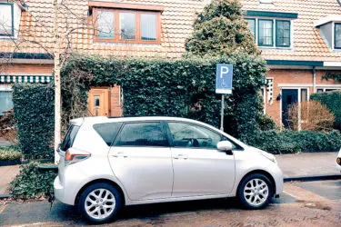 Een zilveren auto staat op een gehandicaptenparkeerplaats.