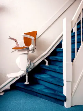 Foto van een traplift langs een trap met vloerbedekking.