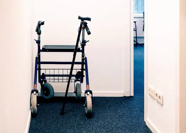 Foto van rollator en loopstok die in de hoek van een gang staan
