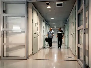 Foto van huisarts en politieagent die door een gang van arrestantencomplex lopen