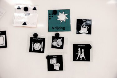 Plaatjes met daarop activiteiten afgebeeld, hangen op een whiteboard.