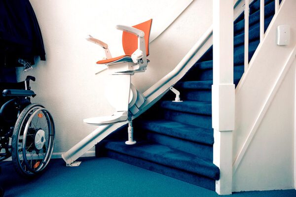 Een traplift zonder passagier staat onder aan de trap.