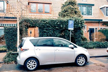 Een zilveren auto staat op een gehandicaptenparkeerplaats.