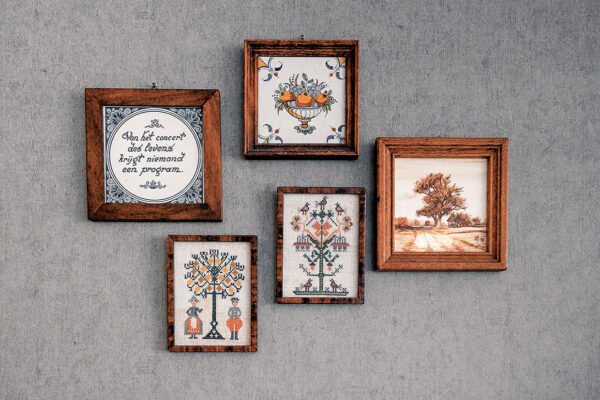 Vijf kleine schilderijen hangen aan een grijze muur.