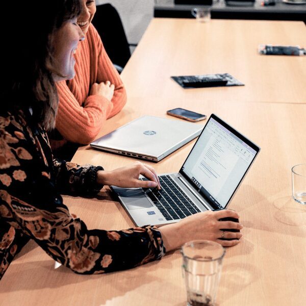 Vrouw zit aan tafel en werkt op haar computer.