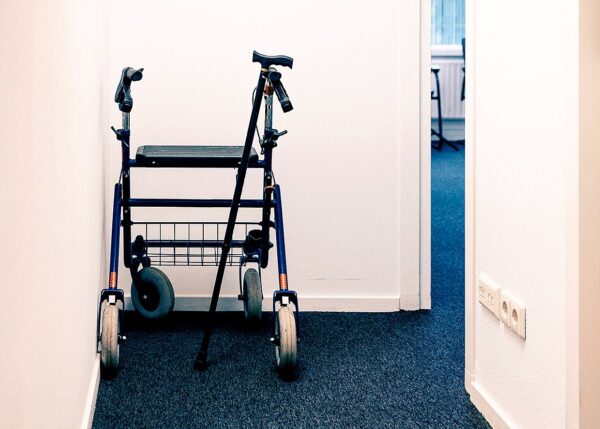Foto van rollator en loopstok die in de hoek van een gang staan