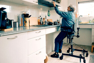 Foto van oudere vrouw in keuken met hulpmiddel op wieltjes
